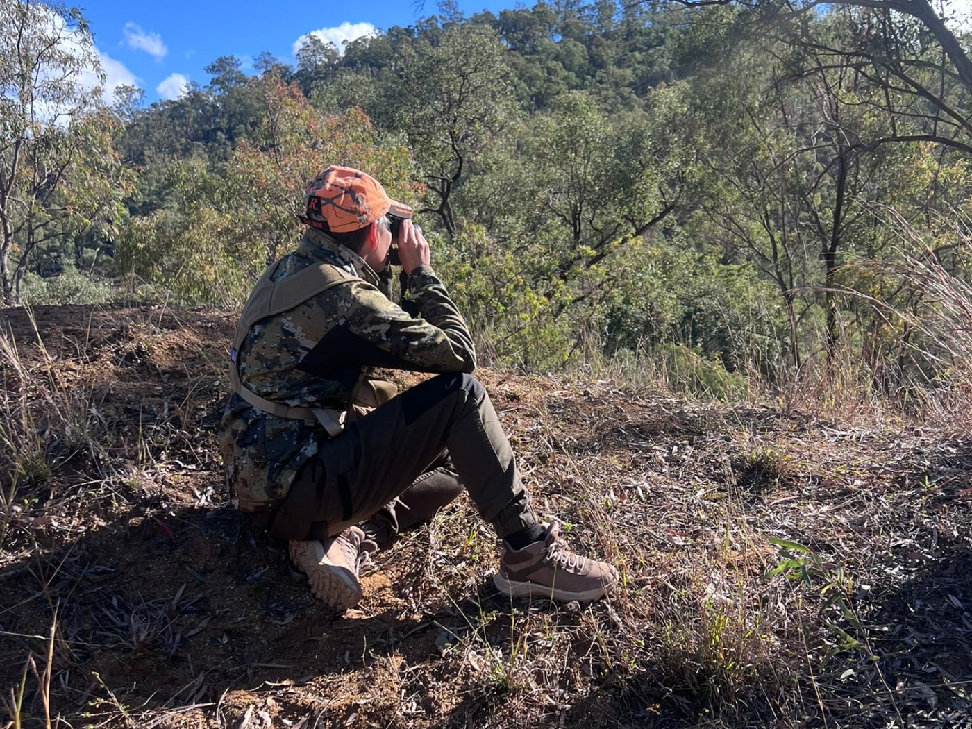 Woman using binoculars while learning field observation skills during a Women Who Hunt weekend.