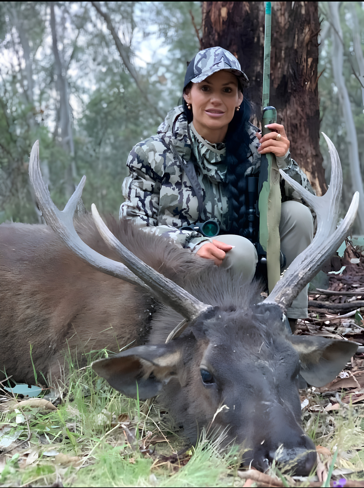 Sharelle Galea kneeling behind a large sambar stag with her rifle