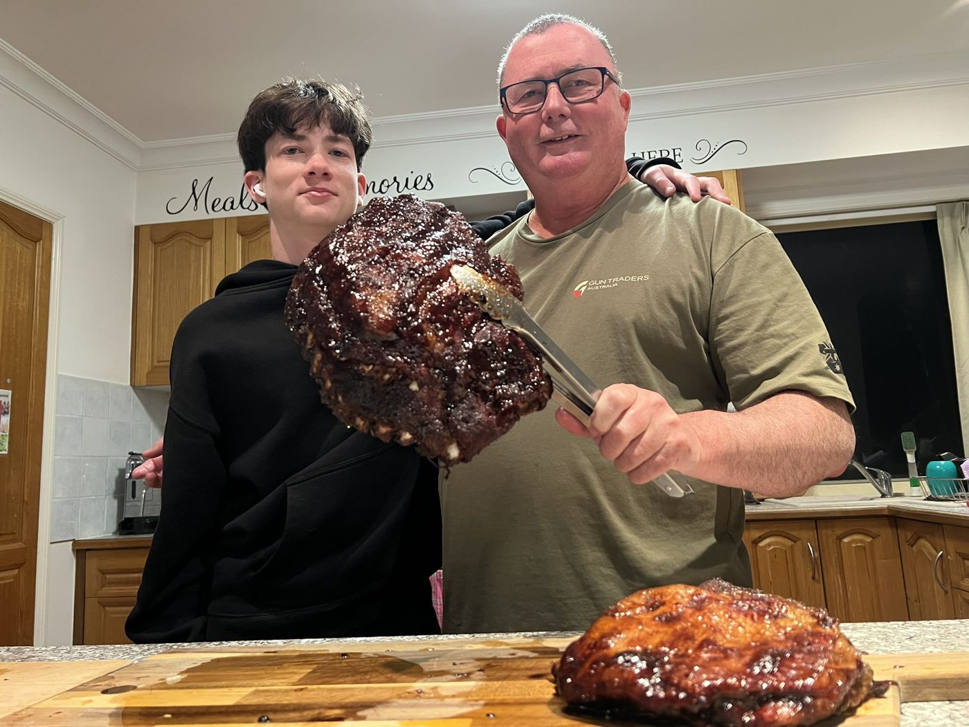 Ethan and Glenn in the kitchen holding up a rack of glazed ribs