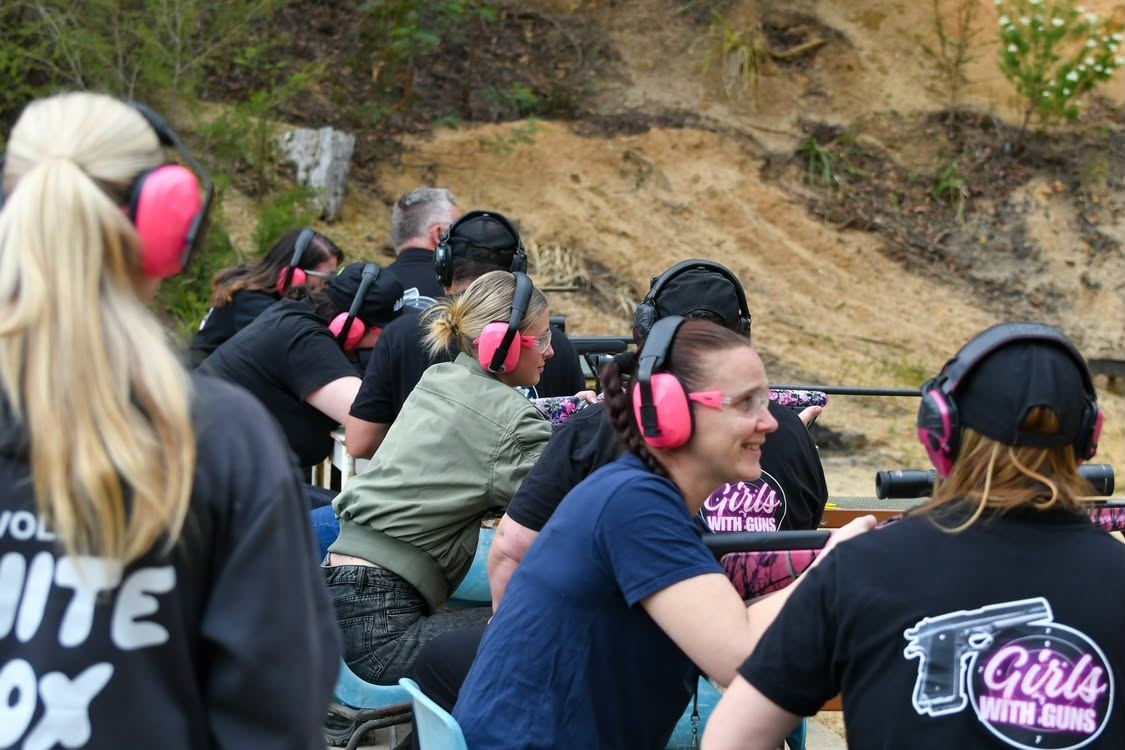 Women in pink earmuffs and Girls with Guns shirts on the rifle firing line