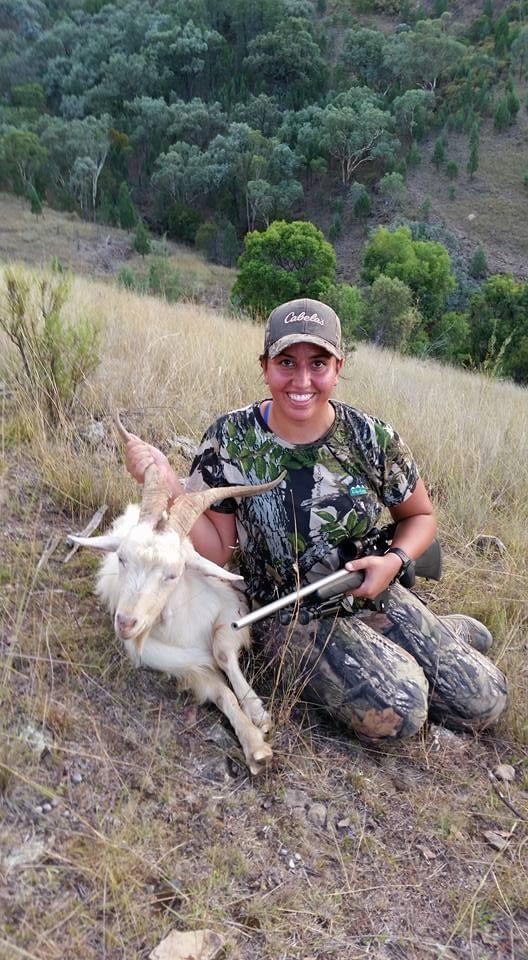 Claire kneeling beside her first goat on a steep hillside