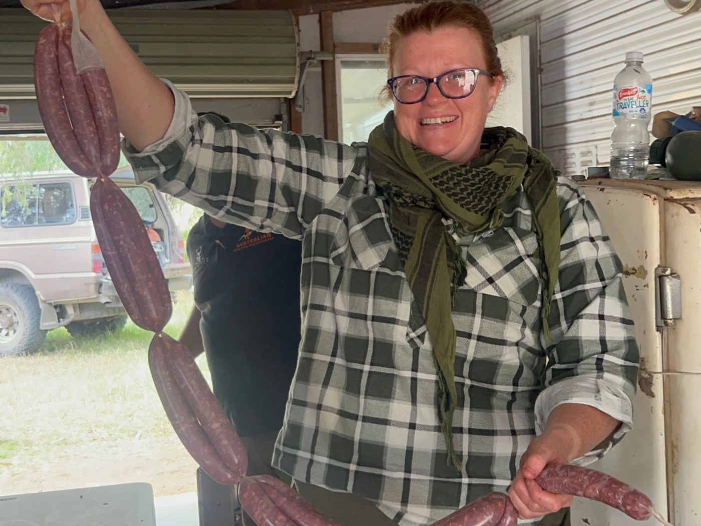 Woman proudly displaying freshly made wild-game sausages during a Women Who Hunt weekend.